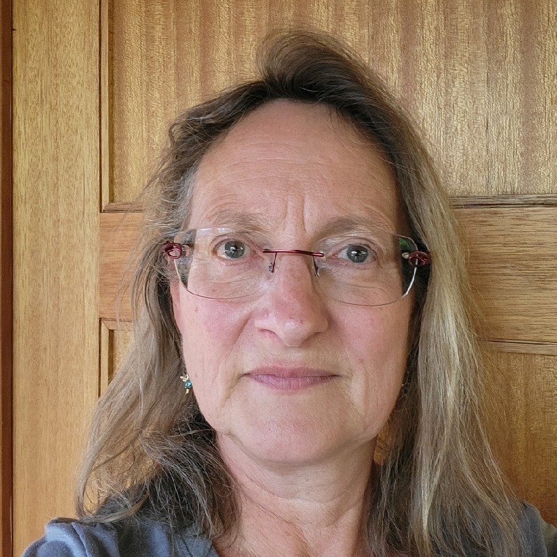 Young businessman and businesswoman walking past a wall of windows while looking at a mobile phone.
